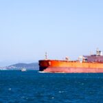 A large cargo ship navigating the open blue sea under a clear sky, showcasing maritime transport.
