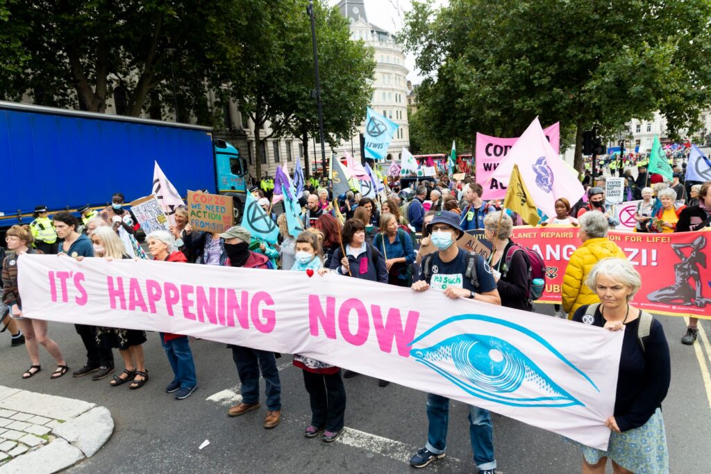 Group of people in masks standing with placards signs flags and banners protesting on on street