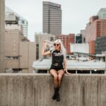 Stylish woman with long blonde hair sitting on a concrete ledge in downtown Cincinnati.