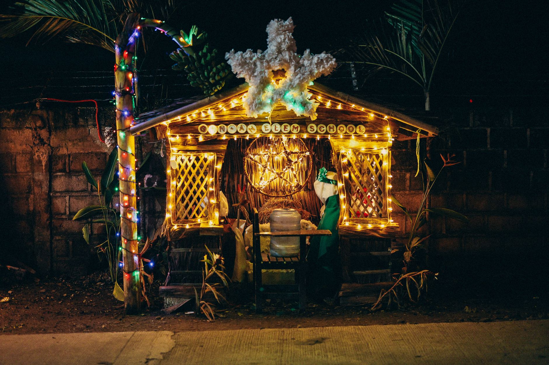 Festive Christmas decoration with lights at a school entrance during night.