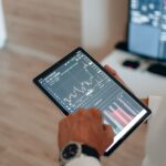 Close-up of hands using a tablet for online trading and market analysis.