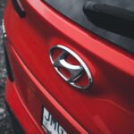Close-up view of a red Hyundai car with a focus on the emblem and rear design.